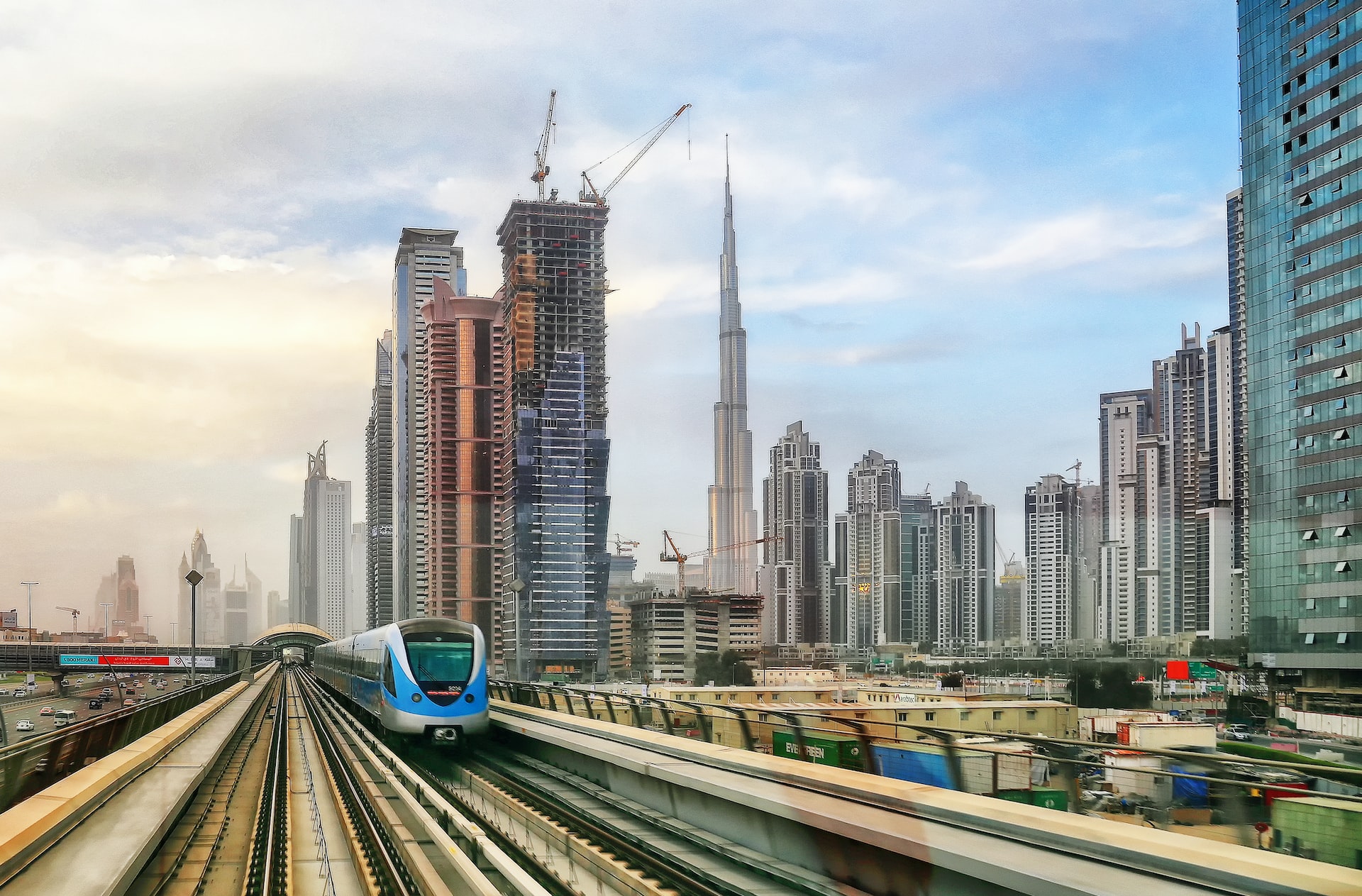 Beginner's guide - a blue Dubai metro train rides on tracks with the city skyline in the background.