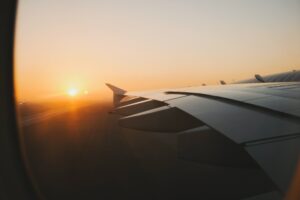 Airplane wing while flying through a sunsetting sky
