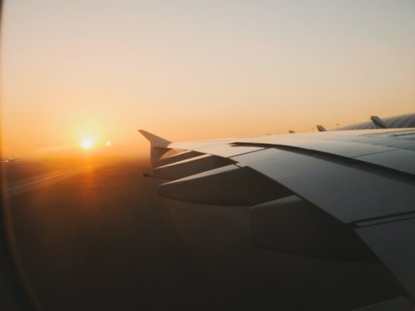 Airplane wing while flying through a sunsetting sky